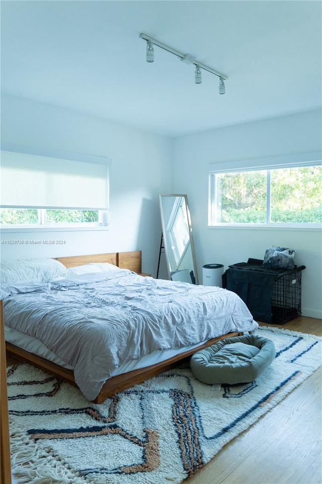 bedroom with rail lighting and hardwood / wood-style flooring