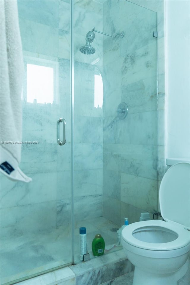 bathroom with an enclosed shower, toilet, and tile flooring