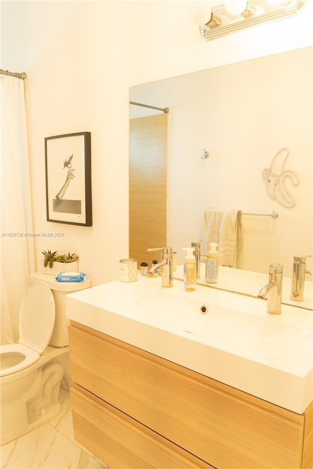 bathroom featuring tile flooring, vanity, and toilet