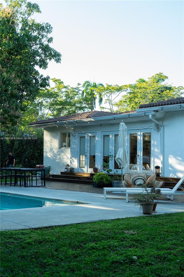 rear view of house featuring french doors, a patio, and a lawn