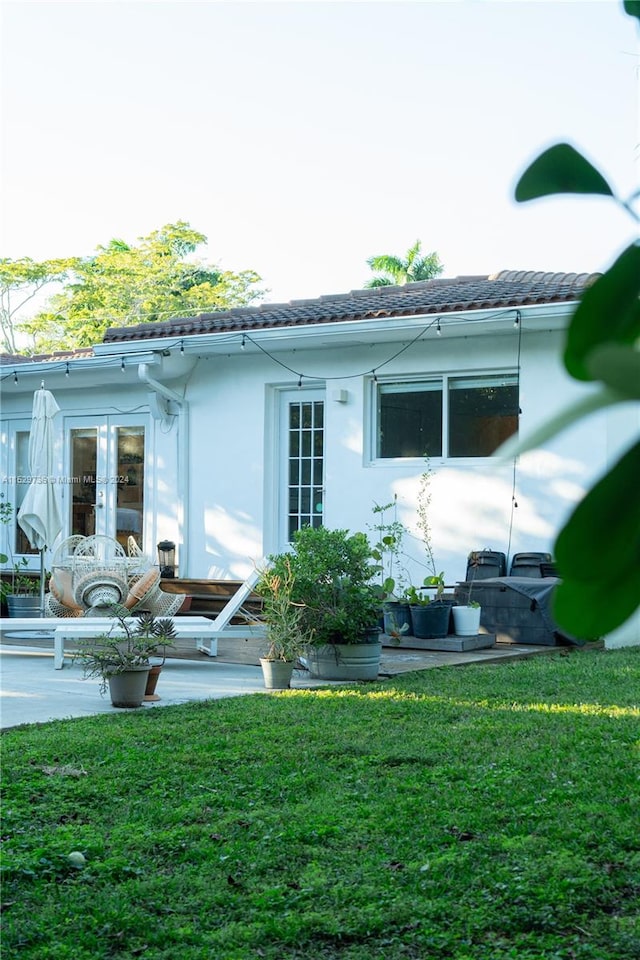 rear view of property featuring a patio, a lawn, and french doors