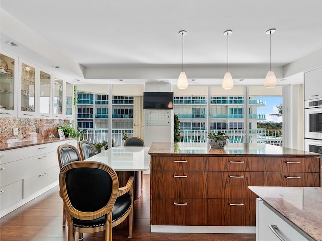 kitchen featuring white cabinetry, stainless steel double oven, a kitchen breakfast bar, and a center island