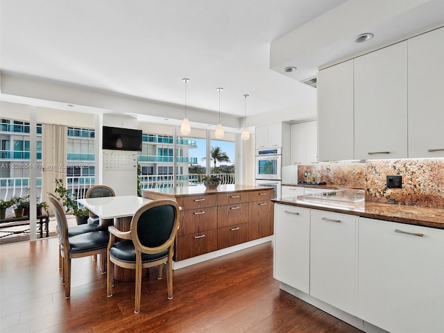 kitchen featuring dark wood-type flooring, white cabinetry, tasteful backsplash, decorative light fixtures, and stainless steel double oven