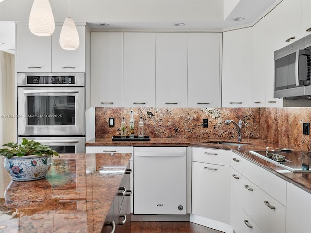 kitchen featuring hanging light fixtures, stainless steel appliances, tasteful backsplash, white cabinets, and dark stone counters