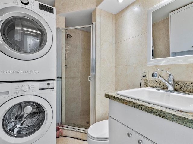 clothes washing area with stacked washer / dryer, sink, and tile walls