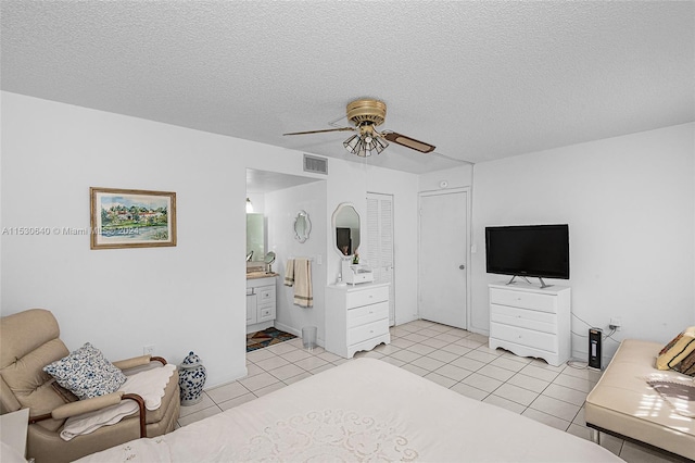 bedroom with connected bathroom, ceiling fan, light tile flooring, a textured ceiling, and a closet