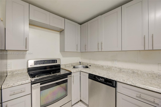 kitchen with light stone countertops, white cabinetry, sink, and stainless steel appliances