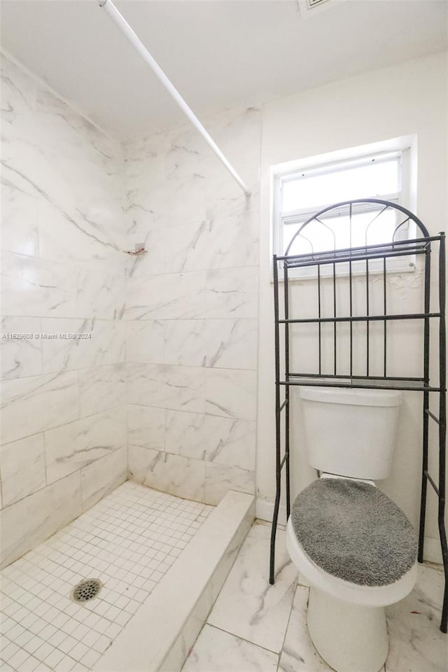 bathroom with toilet, tile floors, and a tile shower