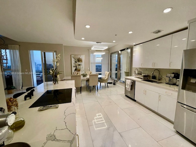 kitchen featuring sink, light tile floors, light stone counters, appliances with stainless steel finishes, and white cabinets