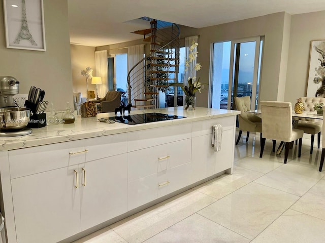 kitchen with light stone countertops, white cabinetry, and black electric stovetop