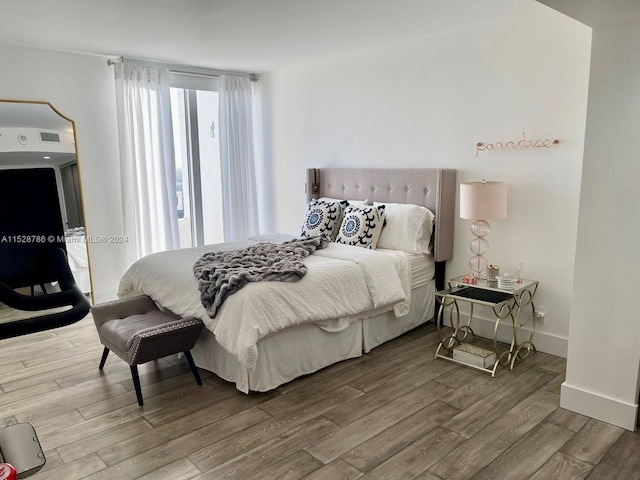 bedroom with multiple windows and wood-type flooring