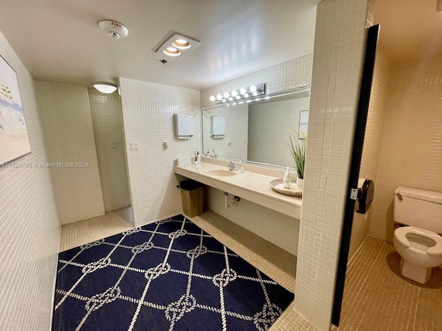 bathroom with toilet, tile floors, tile walls, and sink