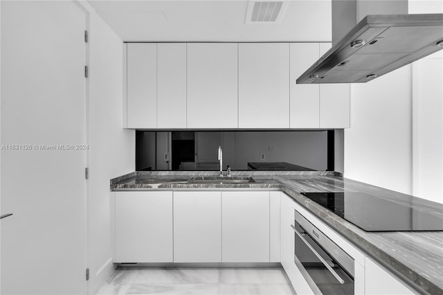 kitchen with light tile floors, oven, white cabinets, island range hood, and black electric stovetop