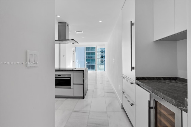 kitchen with extractor fan, oven, wine cooler, white cabinets, and light tile floors