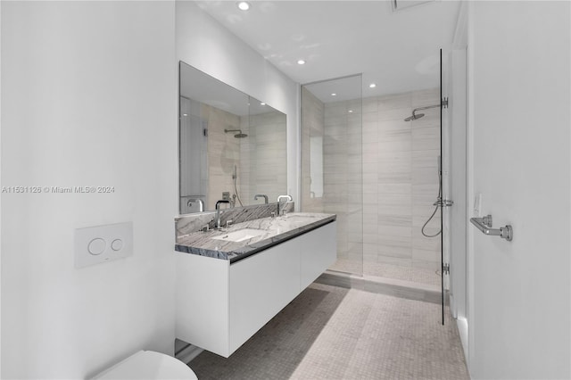 bathroom with large vanity, double sink, and tiled shower