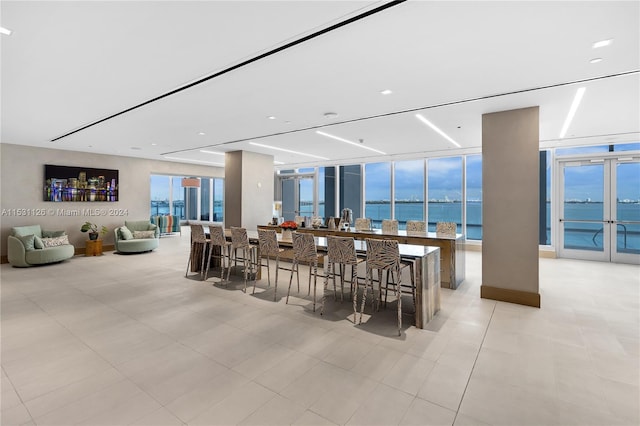 tiled dining area with a water view, floor to ceiling windows, plenty of natural light, and french doors