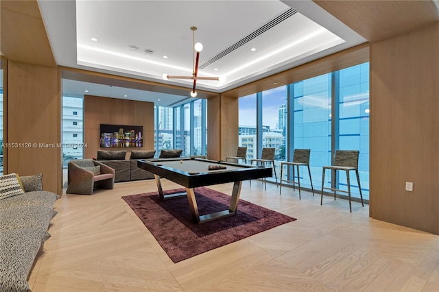 recreation room with a raised ceiling, billiards, floor to ceiling windows, and light parquet floors