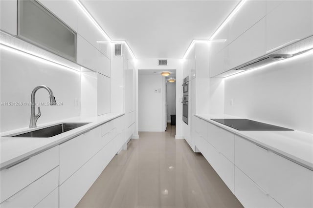 kitchen with sink, white cabinets, black electric cooktop, and double oven