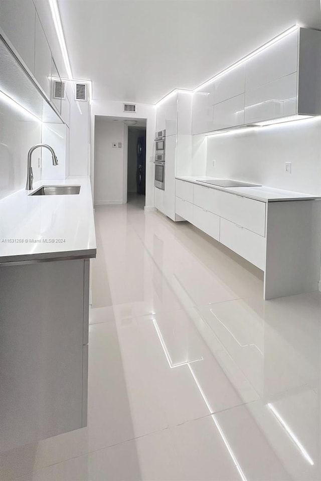 kitchen featuring stainless steel double oven, sink, and light tile floors