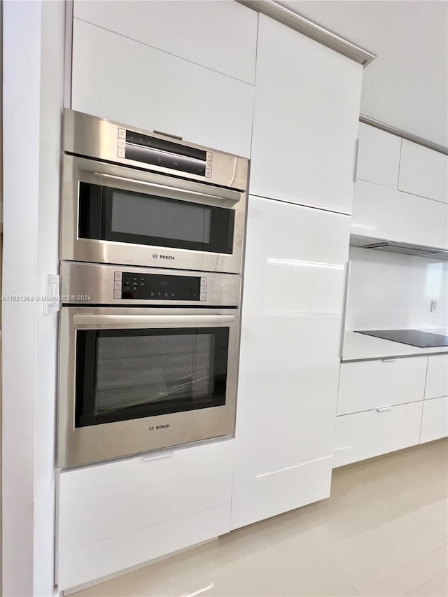 room details featuring stainless steel double oven and white cabinets