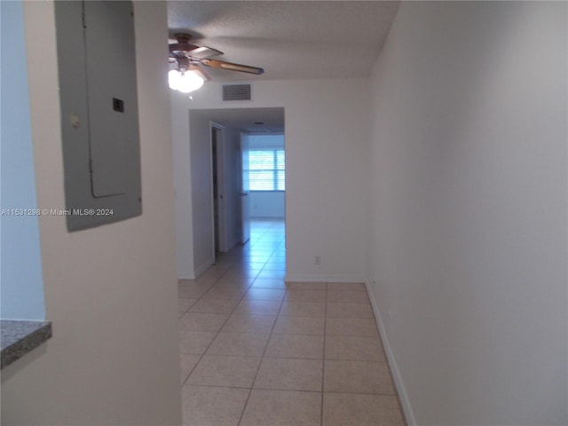 hall with electric panel, light tile patterned floors, and a textured ceiling