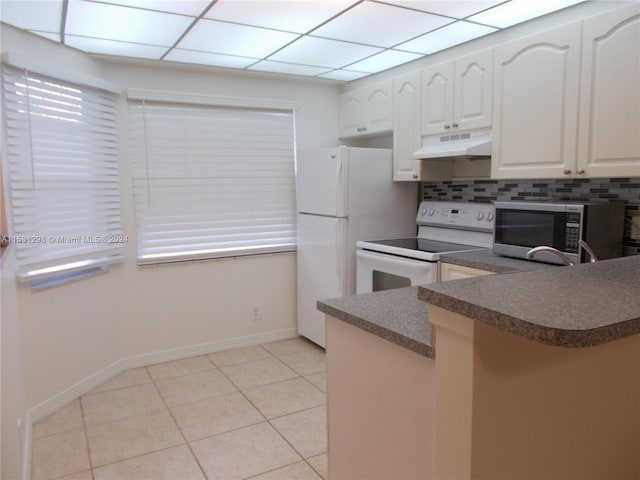 kitchen featuring a paneled ceiling, white appliances, decorative backsplash, light tile patterned floors, and kitchen peninsula