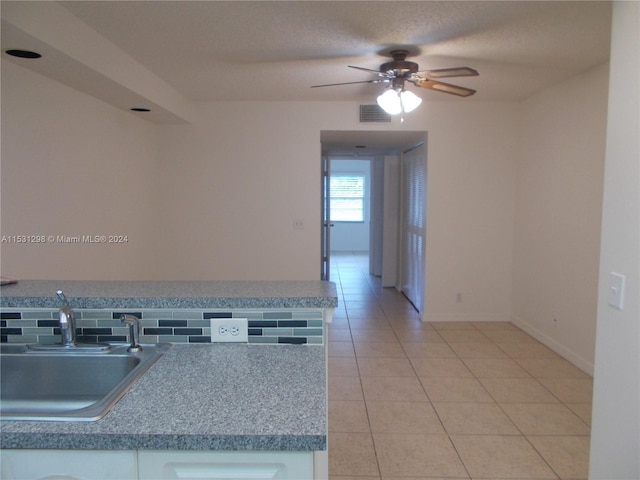 kitchen with sink, a textured ceiling, ceiling fan, and tile patterned floors