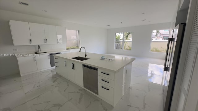 kitchen with stainless steel dishwasher, light tile floors, sink, a kitchen island with sink, and white cabinetry