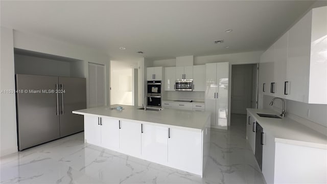 kitchen featuring stainless steel appliances, sink, a center island, and white cabinets