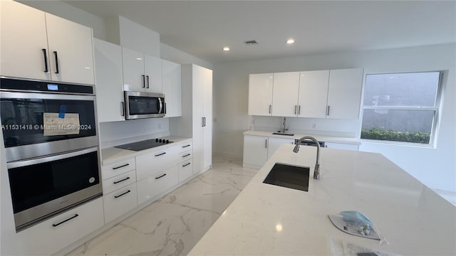 kitchen featuring appliances with stainless steel finishes, sink, white cabinets, and light tile flooring