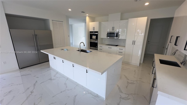 kitchen with an island with sink, stainless steel appliances, sink, and light tile floors