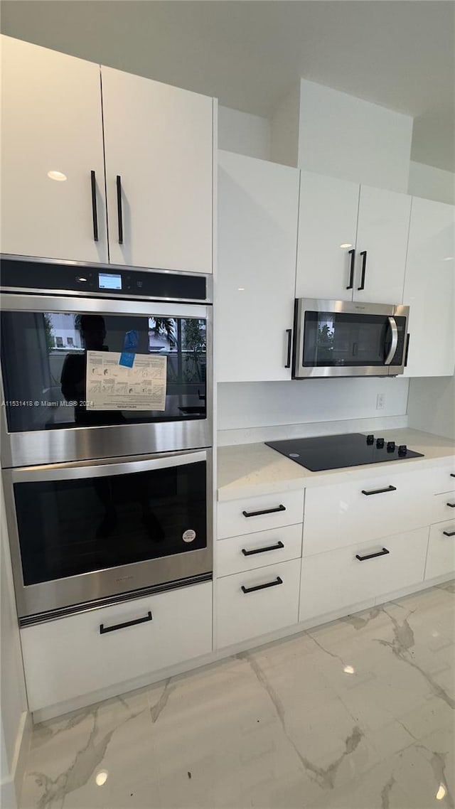 kitchen featuring appliances with stainless steel finishes, white cabinetry, and light tile floors