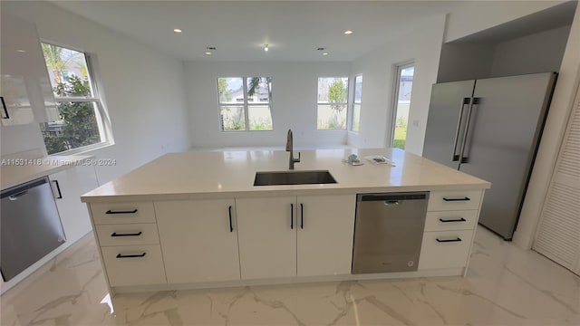 kitchen featuring white cabinetry, stainless steel appliances, an island with sink, sink, and light tile flooring