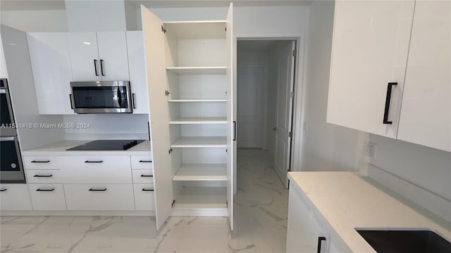 interior space featuring stainless steel appliances, light stone counters, white cabinetry, and light tile floors