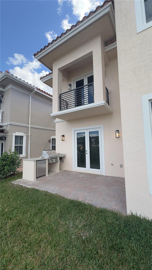 back of house with a patio, french doors, a balcony, and a yard