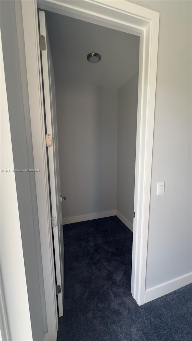 hallway with dark colored carpet