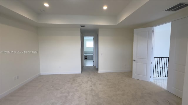 carpeted empty room featuring a raised ceiling