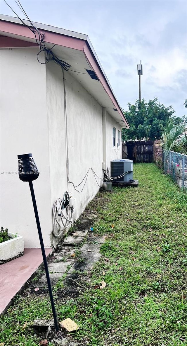 view of property exterior featuring a lawn and central air condition unit