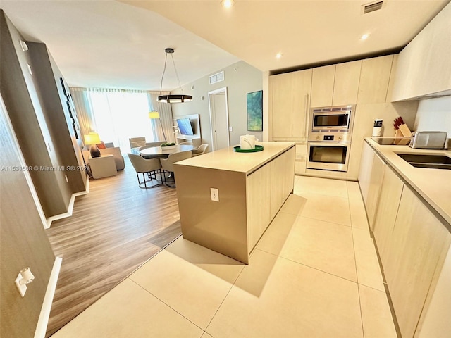 kitchen featuring sink, pendant lighting, a kitchen island, light hardwood / wood-style flooring, and stainless steel appliances