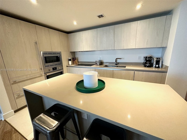 kitchen featuring sink, a kitchen breakfast bar, a kitchen island, stainless steel appliances, and light brown cabinets