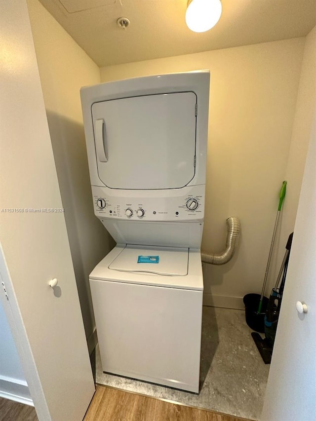 laundry room featuring hardwood / wood-style floors and stacked washing maching and dryer