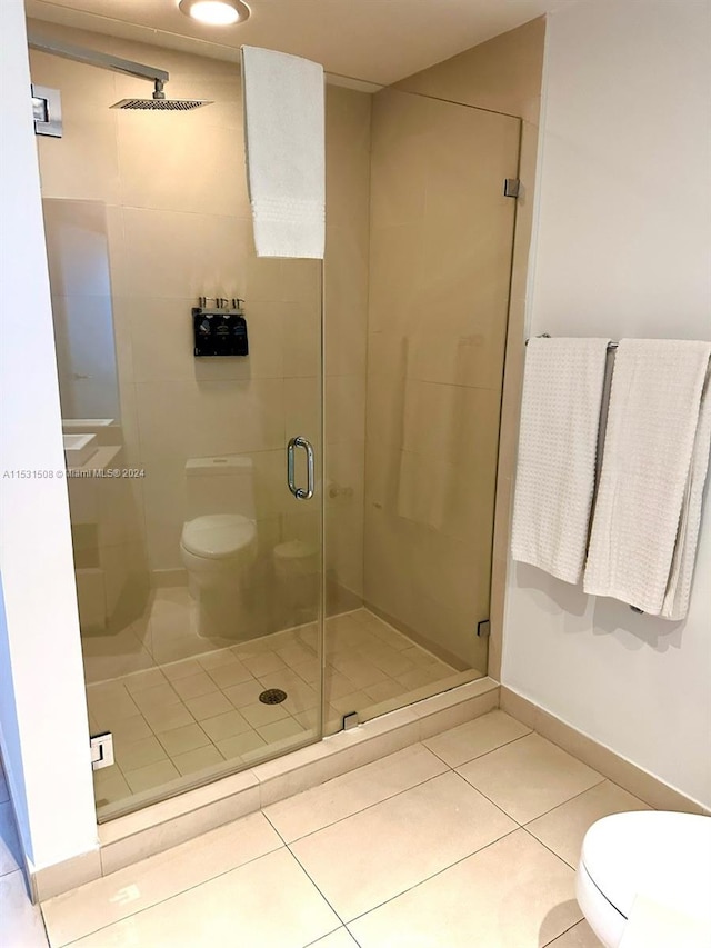 bathroom featuring a shower with door, tile flooring, and toilet