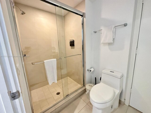 bathroom featuring toilet, tile floors, and a shower with door