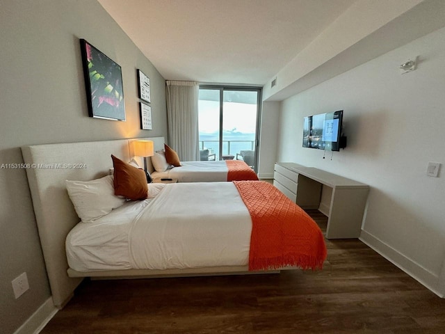 bedroom featuring expansive windows, access to exterior, and dark hardwood / wood-style floors