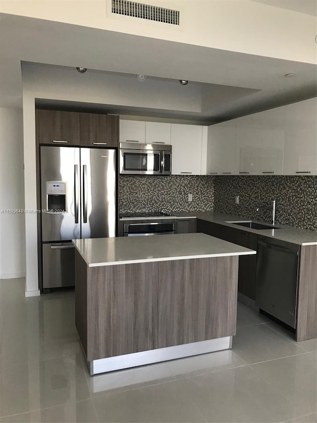 kitchen with tasteful backsplash, white cabinets, appliances with stainless steel finishes, and a center island