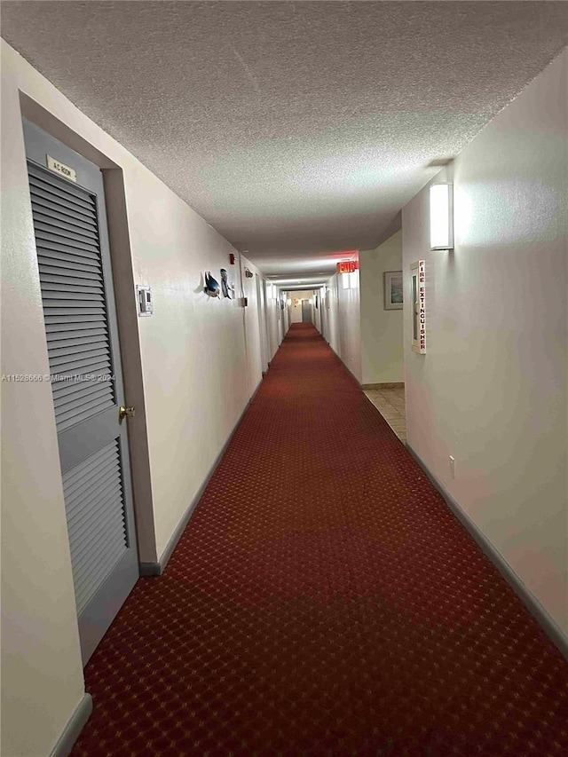 corridor with a textured ceiling and light colored carpet