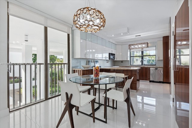 dining area featuring a notable chandelier, light tile floors, and sink