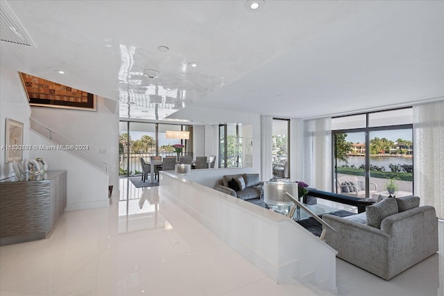 tiled living room featuring a water view and floor to ceiling windows