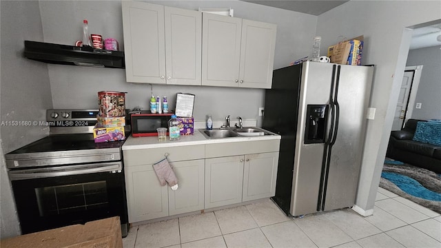 kitchen featuring light tile flooring, stainless steel appliances, white cabinetry, and sink