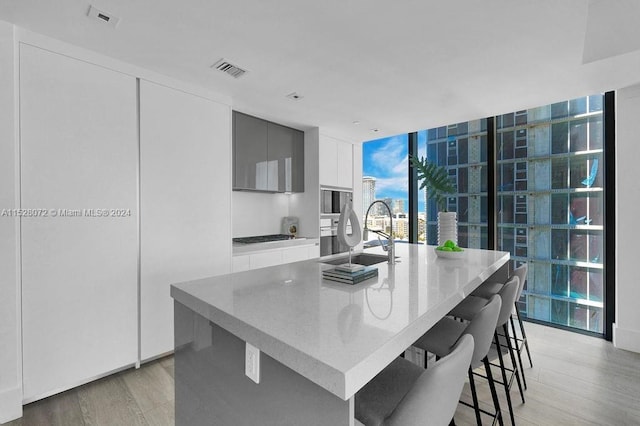 kitchen with a center island with sink, light hardwood / wood-style floors, a breakfast bar, and sink